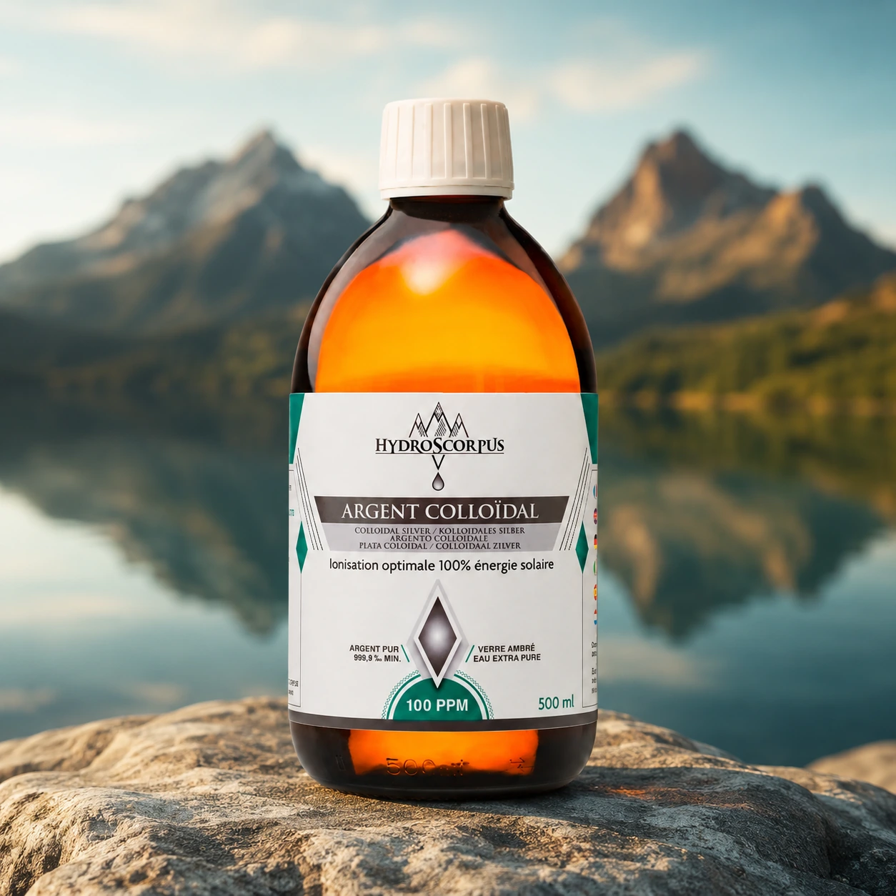 Bouteille d’argent colloïdal Hydroscorpus 100 PPM en verre ambré de 500 ml devant un lac et des montagnes.