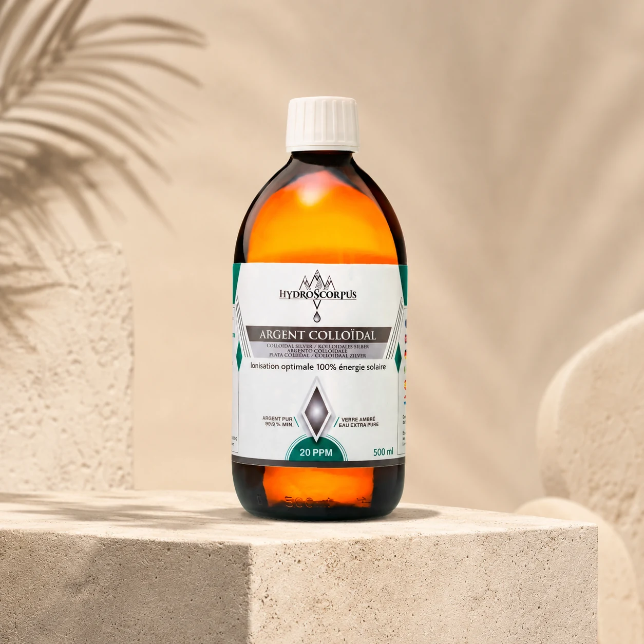 Bouteille d’argent colloïdal Hydroscorpus 20 PPM 500 ml sur support minéral avec tissu et feuillage en arrière-plan.