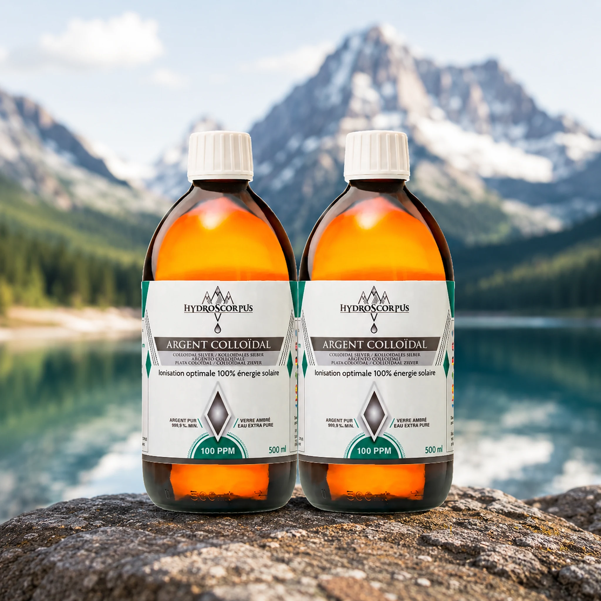 Lot de 2 bouteilles d’argent colloïdal Hydroscorpus 100 PPM en verre ambré 500 ml devant un lac et des montagnes.