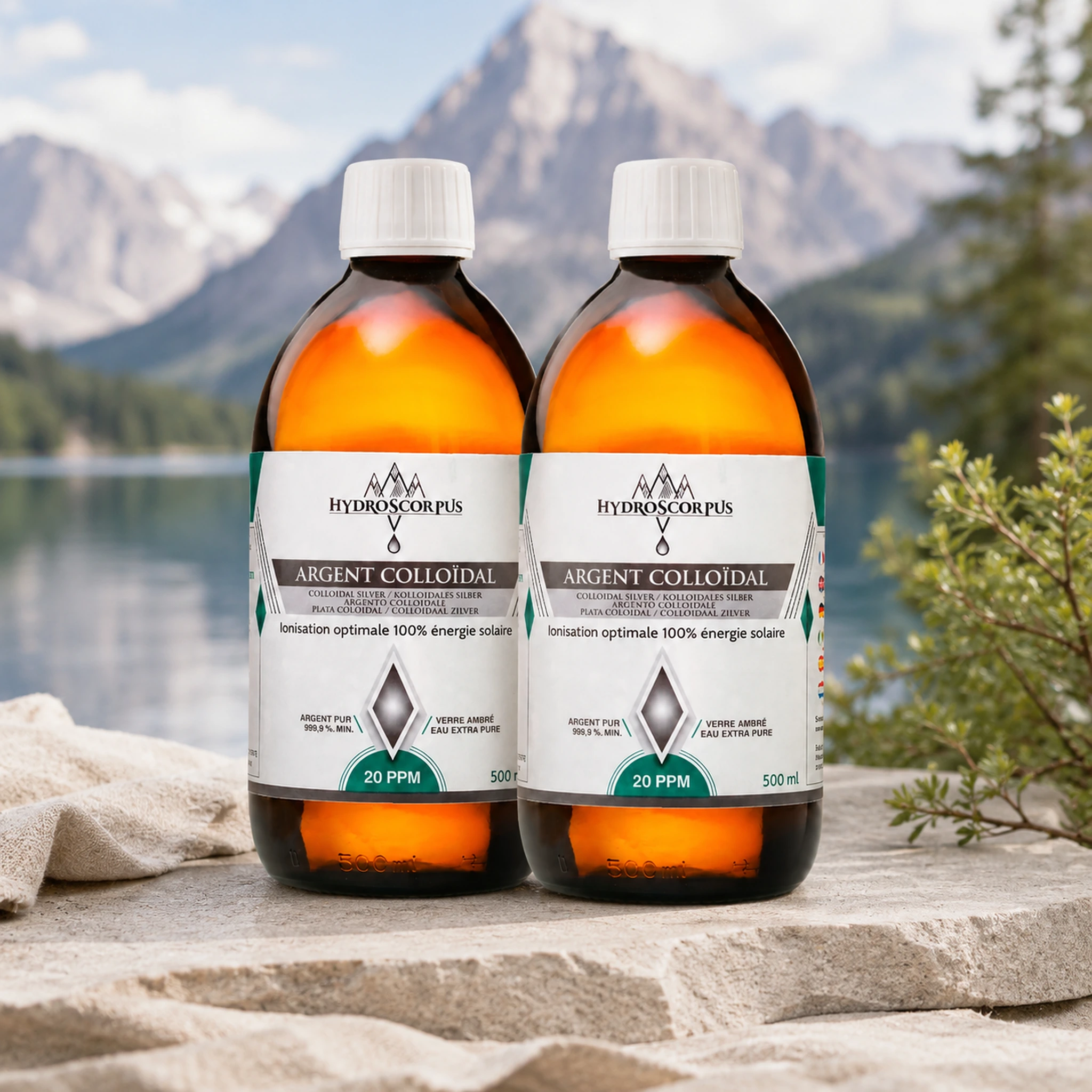 Lot de 2 bouteilles d’argent colloïdal Hydroscorpus 20 PPM en verre ambré 500 ml devant un lac et des montagnes.