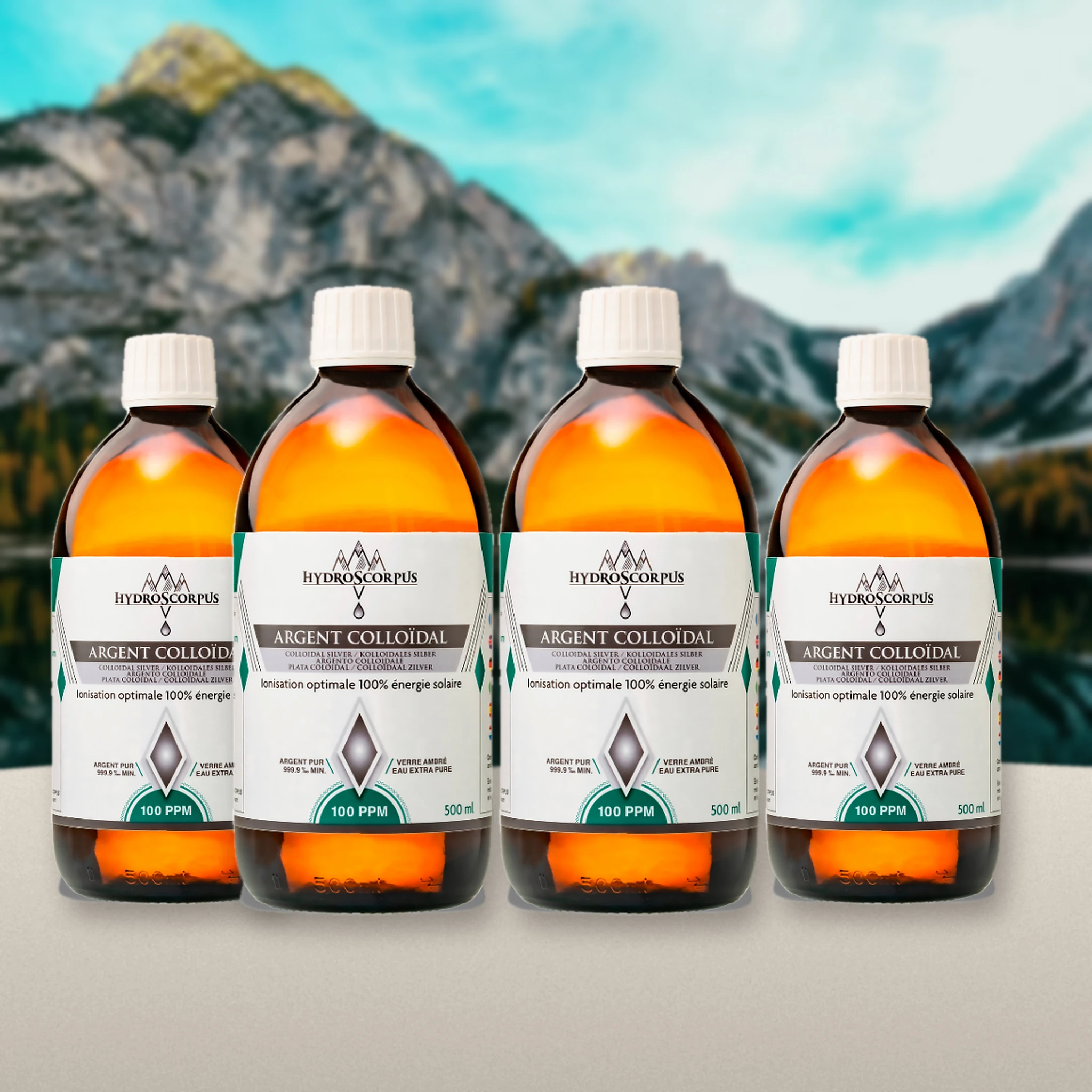 Lot de 4 bouteilles d’argent colloïdal Hydroscorpus 100 PPM en verre ambré 500 ml devant un lac et des montagnes.